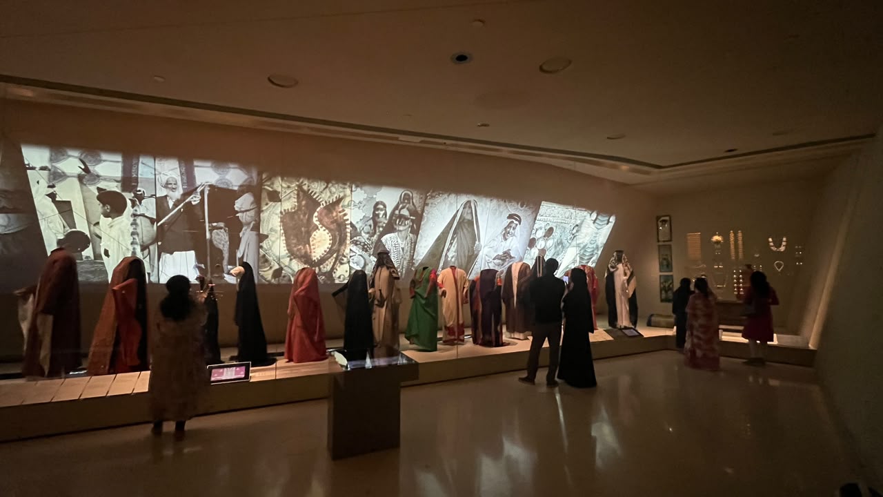 Traditional clothing displayed in front of projected photographs of people.